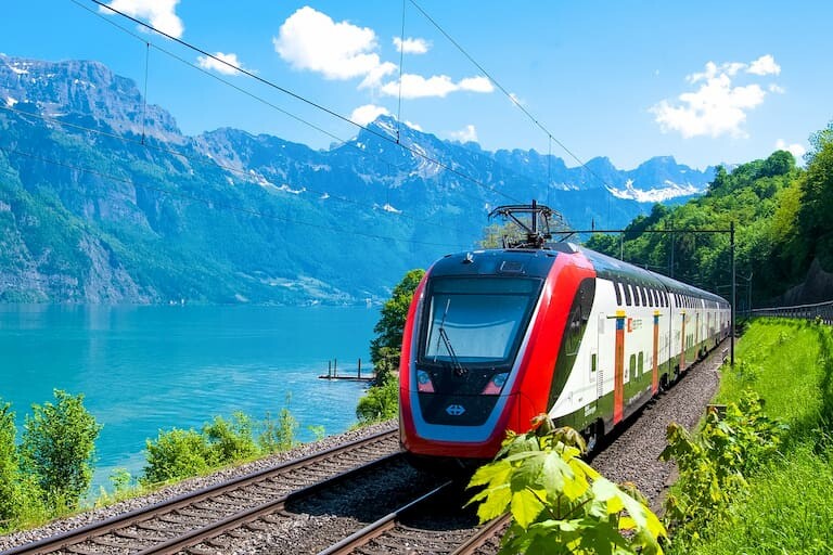 Un tren suizo recorriendo el borde de un lago